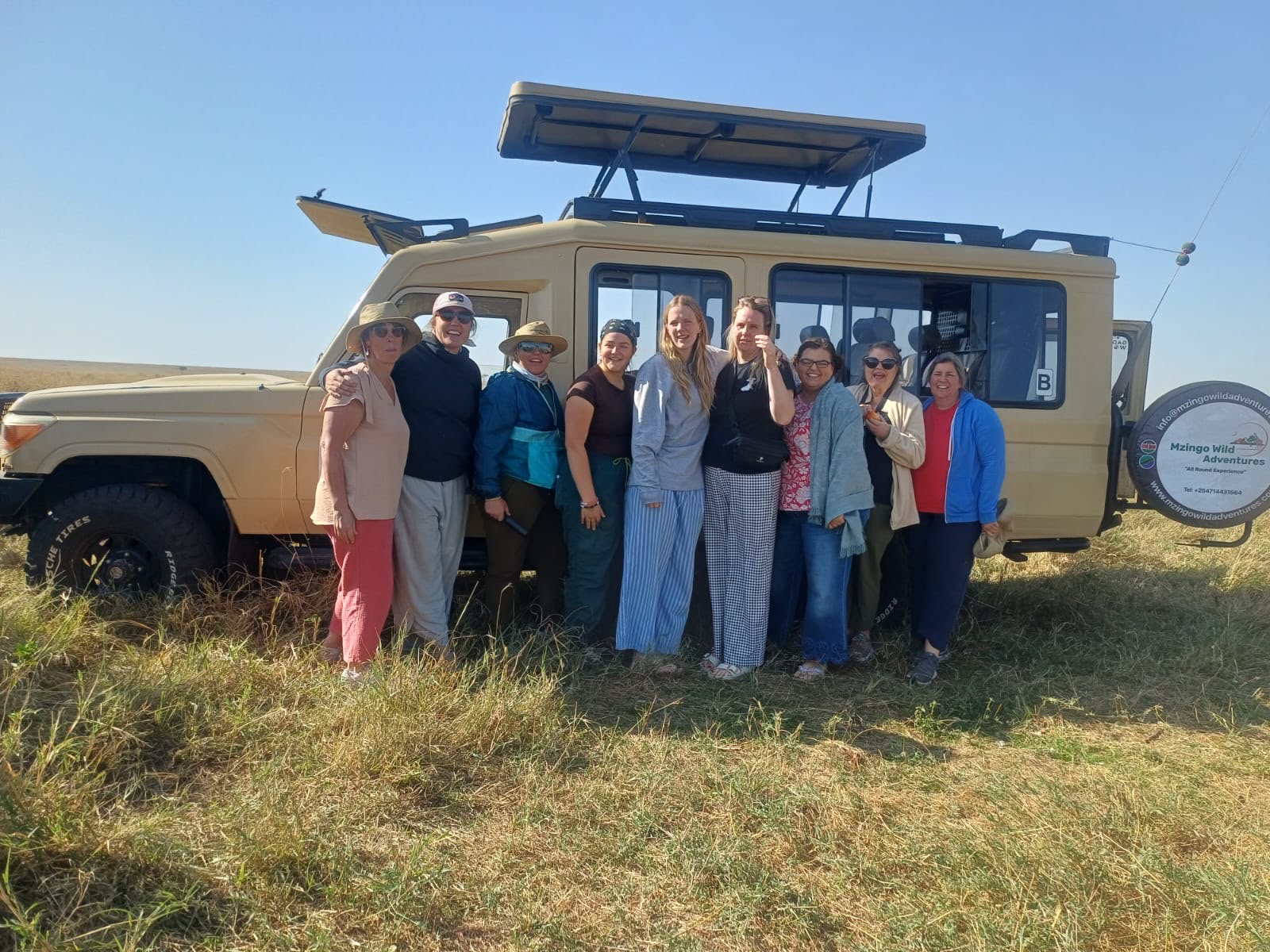 A group of Mzingo guests beside their branded safari vehicle in the Masai Mara