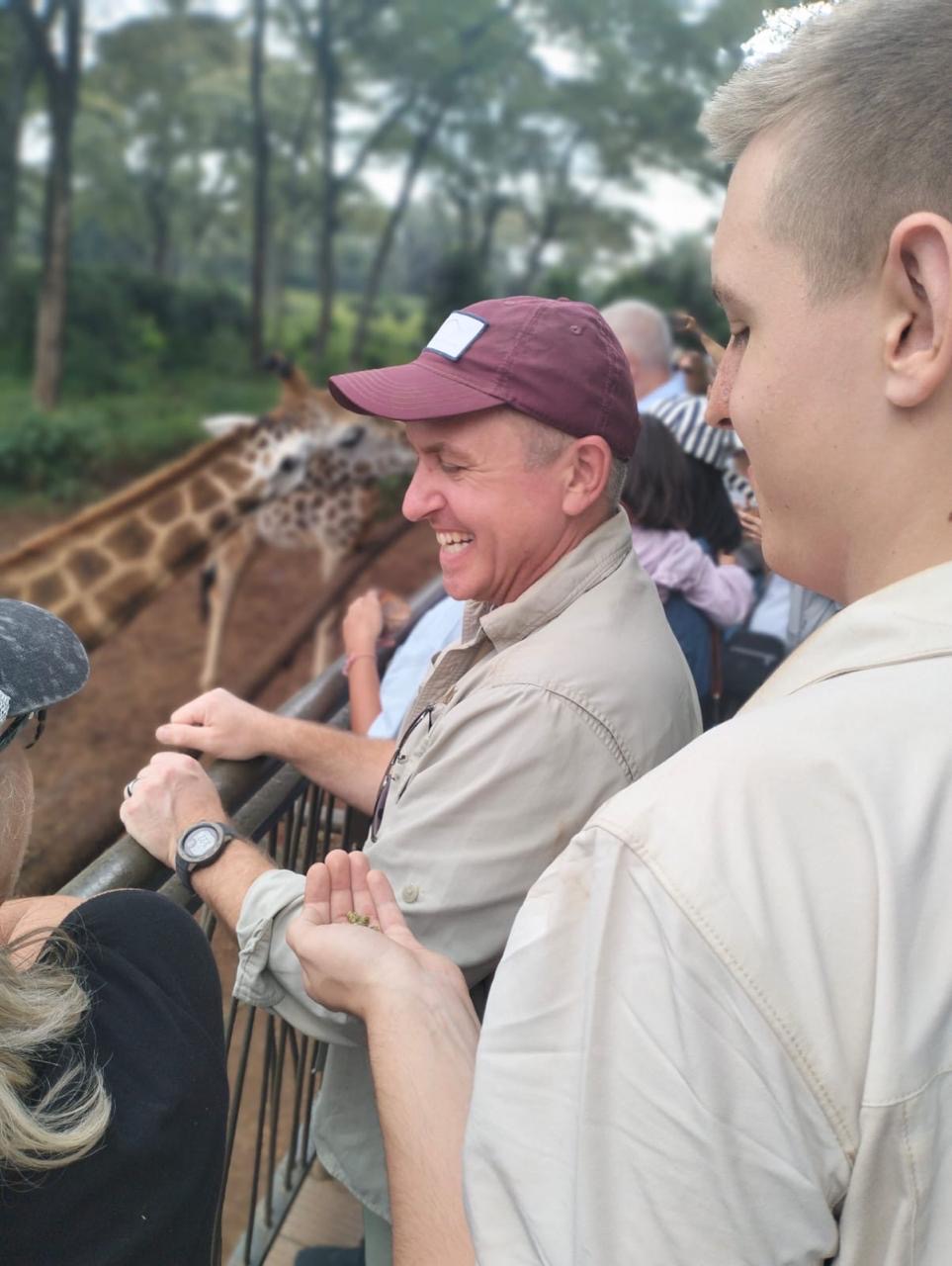 Guests laughing while feeding a giraffe at the Giraffe Centre in Nairobi