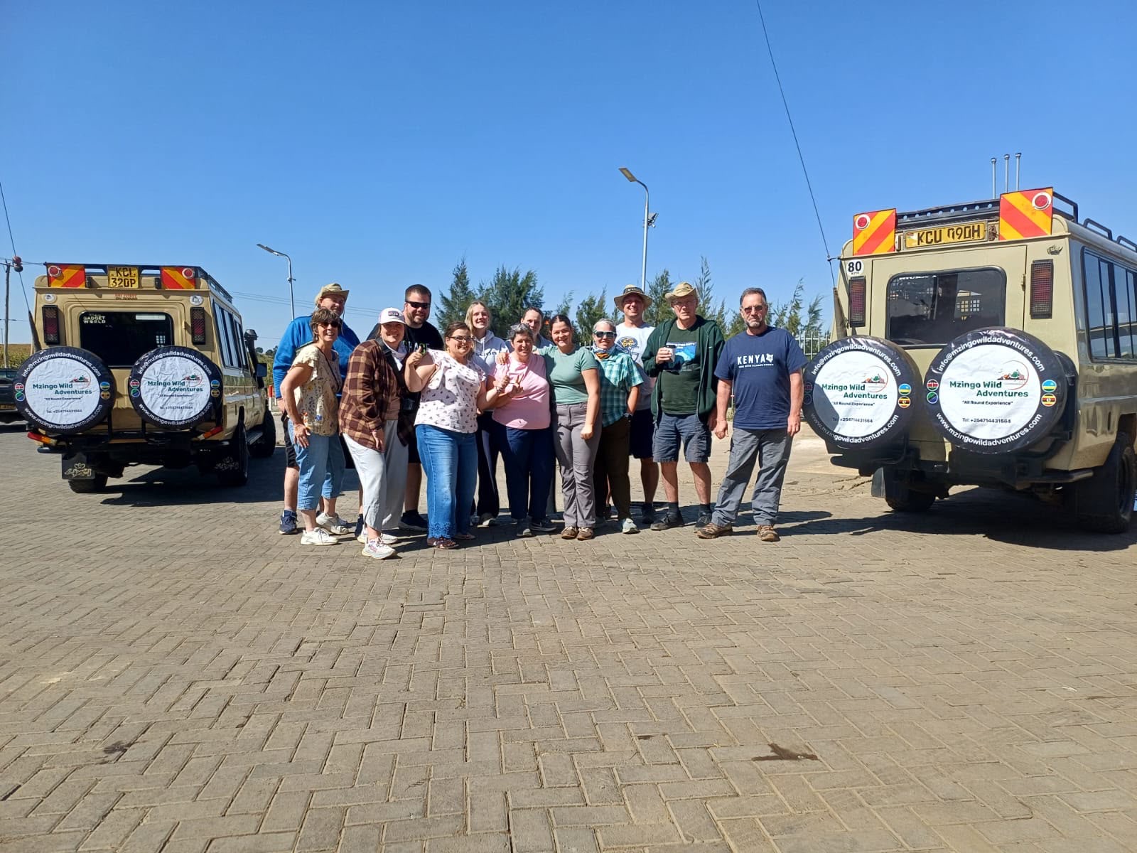 A group of Mzingo guests with their branded safari vehicles at the end of a Kenya safari